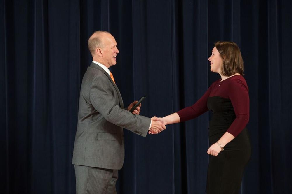 Doctor Potteiger shaking hands with an award recipient in a maroon and black dress